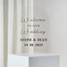 Clear acrylic arch-shaped wedding welcome sign with script and serif text reading "Welcome to our Wedding" and "Steph & Ryan 10 08 2025" displayed on a white pedestal base.