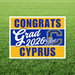 Yard sign with blue and gold horizontal stripes displaying "CONGRATS Grad 2026 CYPRUS" text with a pirate skull and crossbones logo in the center.