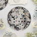 Black and white disco ball-patterned paper plate with colorful mirror tiles arranged in a spherical design, surrounded by smaller silver and clear disco ball decorations on a white background.