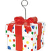 White gift box with colorful polka dots tied with a red ribbon bow, topped with a silver wire loop for hanging balloons.