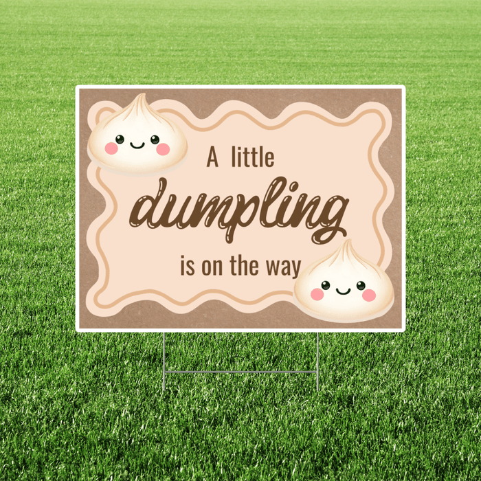 Rectangular yard sign with a warm beige background and wavy border, featuring cute smiling dumpling illustrations and the phrase “A little dumpling is on the way” in playful script, displayed on a lawn with a metal H-stake.