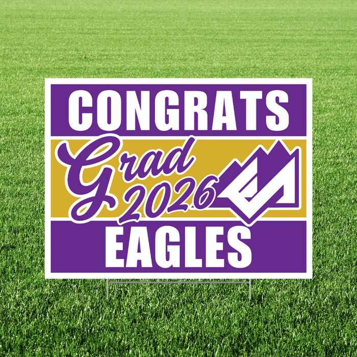 Purple and gold yard sign with white text reading "CONGRATS Grad 2026 EAGLES" and a checkmark graphic on green grass.