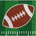 Brown and white football with laces centered on green grass field background with yard line markings at bottom on napkin.