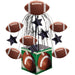 Football-themed centerpiece featuring a green field base with two footballs, topped with a cage structure holding six suspended footballs and navy stars.
