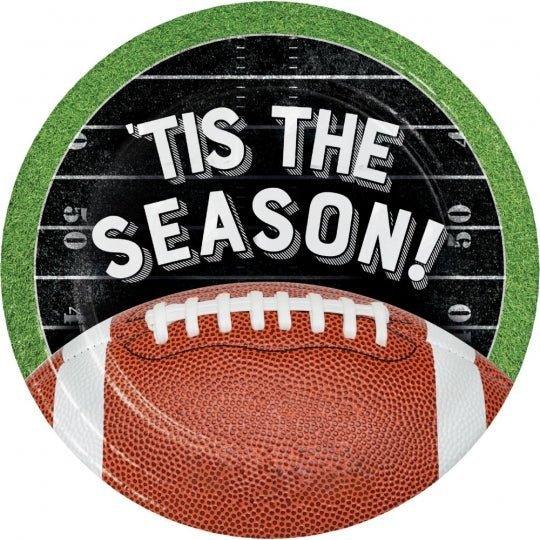 Circular dessert plate with green grass-textured border, black center band with white "'TIS THE SEASON!" text, and brown football with white laces at the bottom.