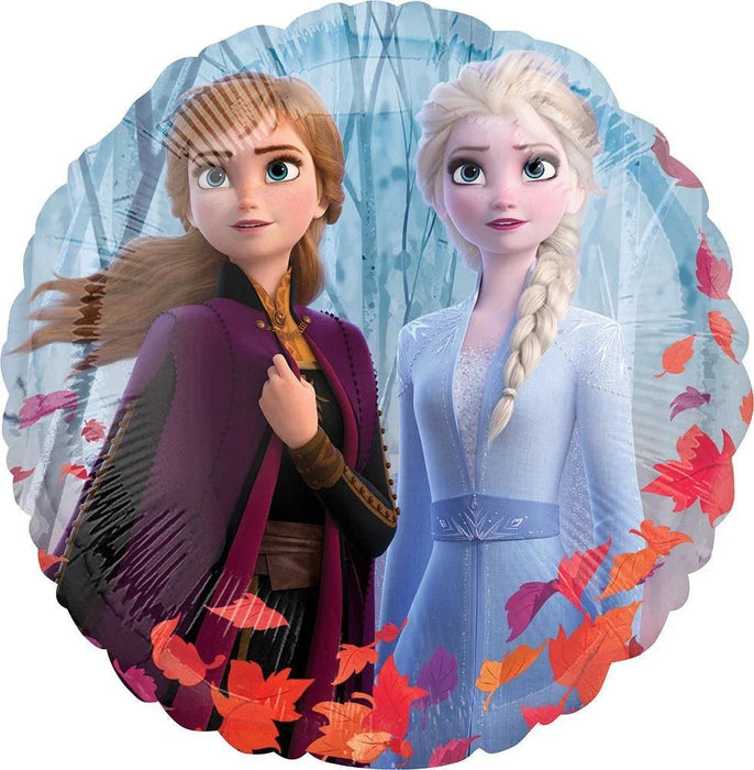 Round foil balloon featuring two animated sisters in winter clothing against a snowy blue background with falling autumn leaves in red and orange tones.