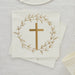 Stack of cream-colored paper napkins featuring a gold cross centered within a delicate botanical wreath design.