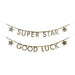 Two gold glitter letter banners with decorative stars strung on thin lines, reading "SUPER STAR" and "GOOD LUCK.