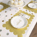 Gold glitter scalloped placemats shown under white celebration plates with gold confetti accents on a party table.