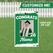 Green yard sign with white text reading "CONGRATS" and "'26" featuring a customizable photo frame and name area, measuring 24 inches by 36 inches.