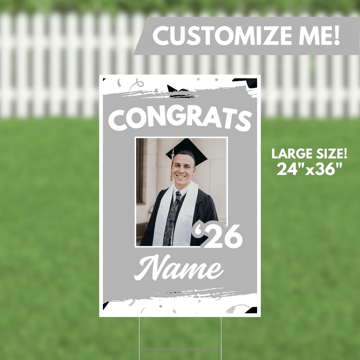 Large silver yard sign measuring 24 by 36 inches with "Congrats" text, a customizable photo frame showing a graduate in cap and gown, the year 2026, and a space for a name at the bottom.