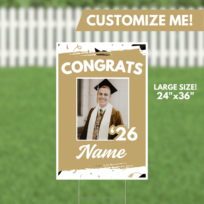 Gold and white graduation yard sign 24 by 36 inches featuring a customizable photo frame with "CONGRATS," the year 26, and a name placeholder, displayed against a white picket fence and green grass background.