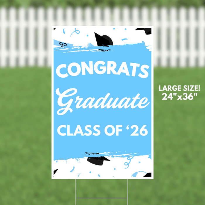 Large blue yard sign with white text reading "CONGRATS Graduate CLASS OF '26" decorated with black graduation caps and blue confetti designs.