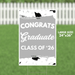 Large yard sign with gray background featuring white text reading "CONGRATS Graduate CLASS OF '26" decorated with black graduation caps and confetti designs, measuring 24 inches by 36 inches.