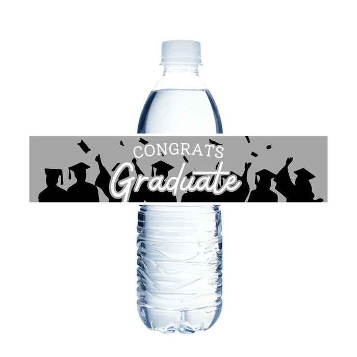 A plastic water bottle wrapped with a gray "Congrats Graduate" label featuring silhouettes of graduates in caps and gowns with confetti.