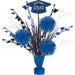 Blue graduation centerpiece with three blue tinsel pom-poms, black and white feathered picks, and a mortarboard cap topper in a blue base.