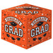 Bright orange cubic gift box with "Congrats Grad" text, black mortarboard caps, white and black stars, and confetti pattern on all visible sides.