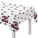 White plastic tablecloth with scattered black graduation caps and maroon ribbons, featuring "Congrats Grad" text in maroon and gray, draped over a white table.