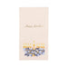 Cream-colored guest towel napkin featuring "Happy Hanukkah" text in gold script at the top and an illustrated menorah with nine golden candles and blue flowers at the bottom.