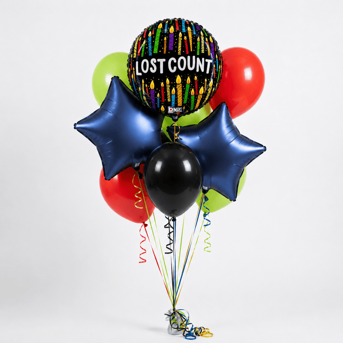 Colorful balloon bouquet featuring a central "Lost Count" sphere with candle designs, navy star-shaped balloons, lime green and red round balloons, a black sphere, and curled ribbon strings in coordinating colors.