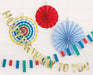 Gold "Happy Birthday to You" garland with colorful flag bunting, red accordion fan, light blue polka dot fan, and yellow striped circular fan displayed against white brick backdrop.