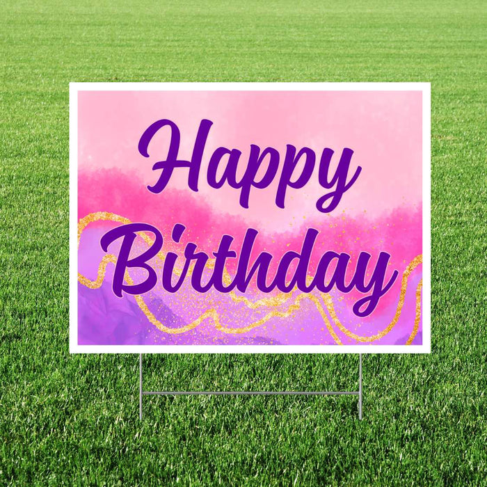 Colorful yard sign with white border displaying "Happy Birthday" in purple script text on a watercolor gradient background in pink, magenta, and purple with gold glitter accents.