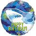 Round mylar balloon featuring a blue shark with open mouth and white teeth against a blue starry background with green accents and green "Happy Birthday" text.