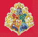 Red beverage napkin featuring the Hogwarts School of Witchcraft and Wizardry crest with gold filigree border, colorful house emblems, and decorative lion and serpent designs.