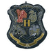 Black shield-shaped mylar balloon featuring the Hogwarts crest with four house emblems, a central H, and gold banner text on a dark starry background.