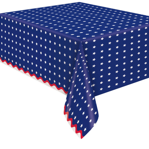 Patriotic paper tablecover with navy blue background, white star pattern, and red scalloped border on a table.