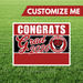 Red and black yard sign with white text reading "CONGRATS Grad 2026" and a red jaguar mascot logo, mounted on a white border frame with metal stakes.