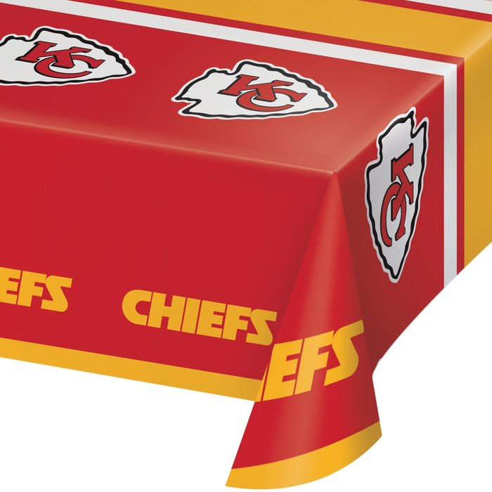 Red plastic table cover with Kansas City Chiefs arrowhead logos in white and gray, gold and red striped borders, and yellow "CHIEFS" text repeated along the edges.