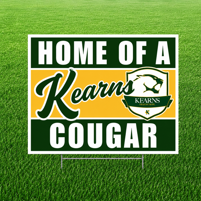 Kearns Cougars "Home of a Kearns Cougar" graduation yard sign displayed on a green grass lawn. The square sign features bold dark green and white text with a gold center stripe, the Kearns script logo, the official Kearns High School cougar crest, and includes an H-stake for easy yard installation.