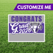 Purple and gray yard sign with white bull mascot logo and "Congrats Grad 2026" text on green grass background.