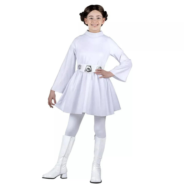 Child wearing a white long-sleeved dress with decorative belt, white tights, white knee-high boots, and hair styled in two buns, smiling at the camera against a white background.