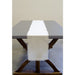 Cream linen table runner with frayed edges draped down the center of a dark wood dining table with X-shaped legs.