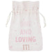 White drawstring pouch with pink stars and text reading "ONE AND LOVING IT" in pink letters scattered across the front.