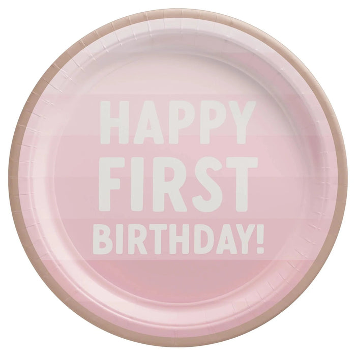 Pink round paper plate with white text reading "Happy First Birthday" and a tan ribbed border.