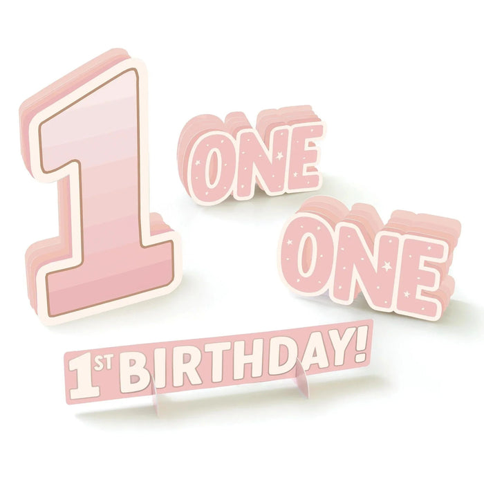 Pink three-dimensional cardstock decorations including a large numeral 1, "ONE ONE" text with stars, and "1ST BIRTHDAY!" banner for first birthday celebrations.