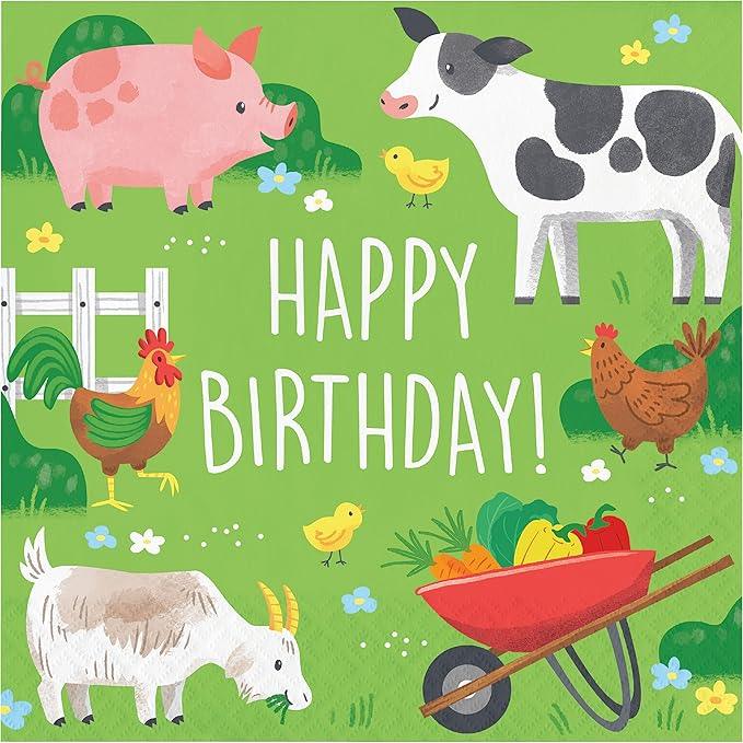 Bright green napkin featuring colorful farm animals including a pink pig, black and white cow, roosters, goats, chicks, and a red wheelbarrow filled with vegetables, with "Happy Birthday!" text in white.