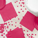 Bright magenta paper napkins arranged on white wood with matching pink plate, confetti, and white frosted cake visible in the arrangement.