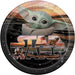 Round paper plate featuring Baby Yoda character in center with Star Wars logo and desert landscape scenes in warm sunset tones against black starry background.