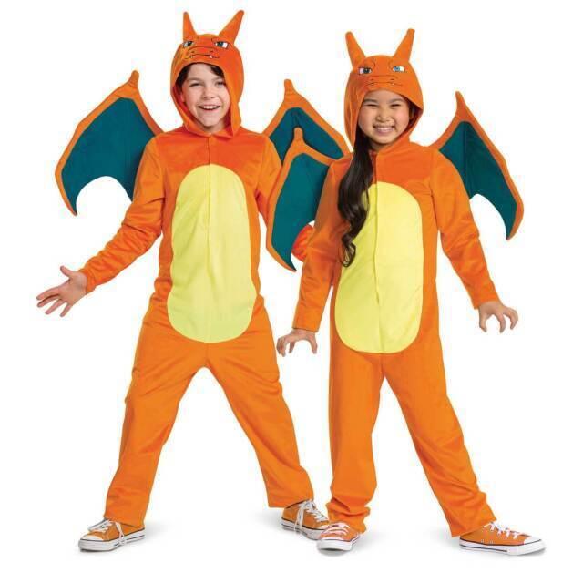 Two children wearing orange and yellow dragon costumes with teal wings, pointed ears, and clawed hands posed against a white background.