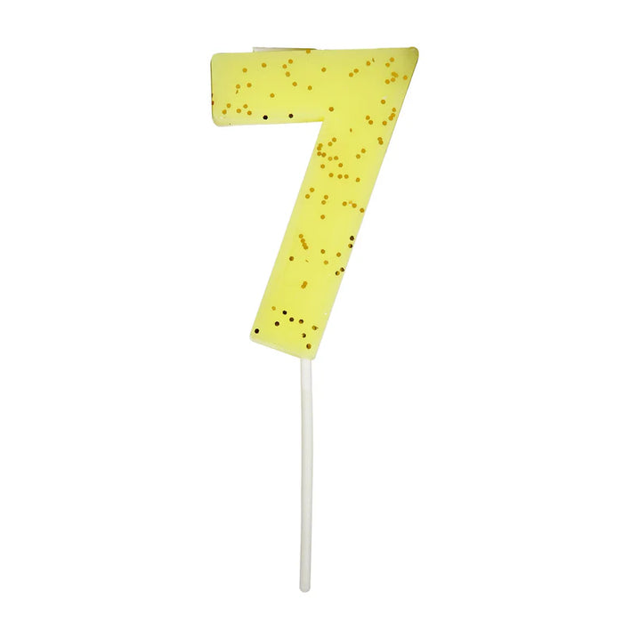 Yellow number 7 cake candle with gold speckle accents and white pick on a white background.