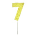 Yellow number 7 cake candle with gold speckle accents and white pick on a white background.