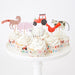On The Farm Cupcake Kit with frosted cupcakes decorated with farm animal and tractor toppers on a white cake stand.
