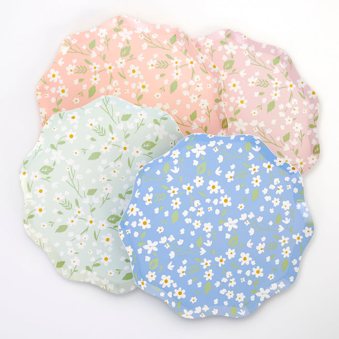 Ditsy Daisy Dinner Plates in assorted pastel pink, peach, mint, and blue colors with white daisy prints, green leaves, and scalloped edges on a white background.