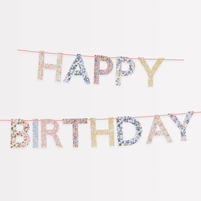 Liberty Floral Happy Birthday Garland with floral-patterned letters spelling Happy Birthday on pink cord.
