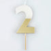White number 2 cake candle with metallic gold dipped finish and wooden pick on a white background.