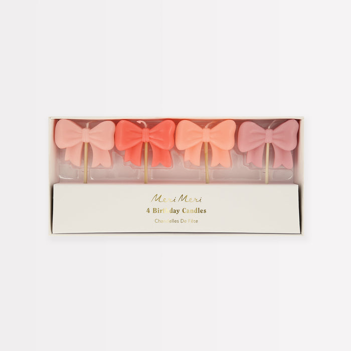Pink Bow Candles in four assorted pastel shades, including soft pink, coral, peach, and mauve, displayed in a box.
